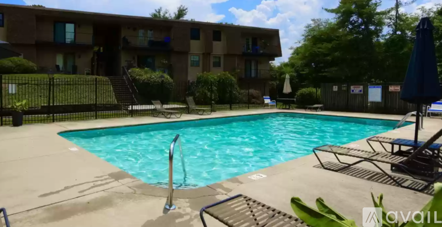 A swimming pool in front of a building with a blue umbrella.