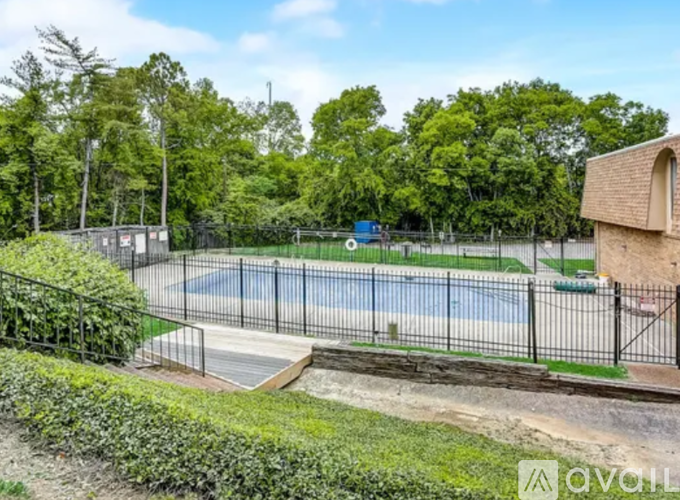 A tennis court surrounded by a fence and greenery.