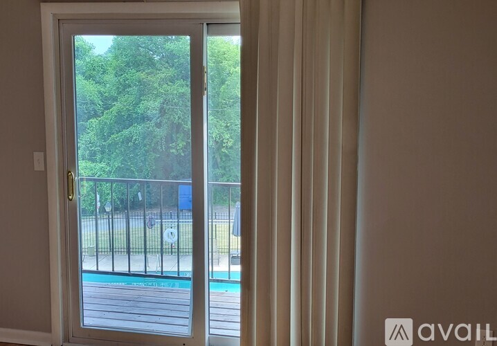 A white door with a glass window leading to a pool and trees.