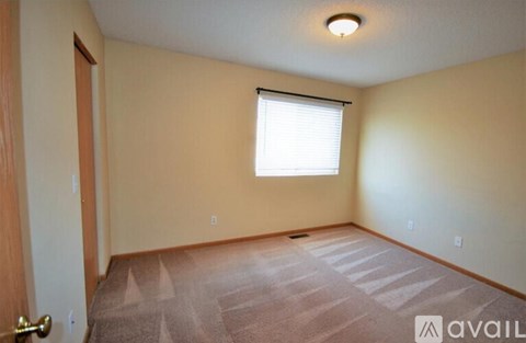 A room with a carpeted floor and a window with blinds.