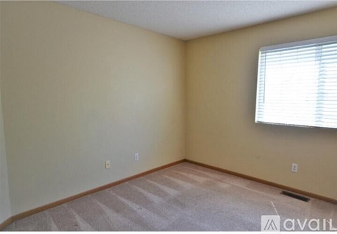 A room with a carpeted floor and a window with blinds.