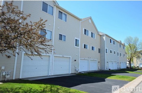 A row of townhouses with garages and a tree in front.
