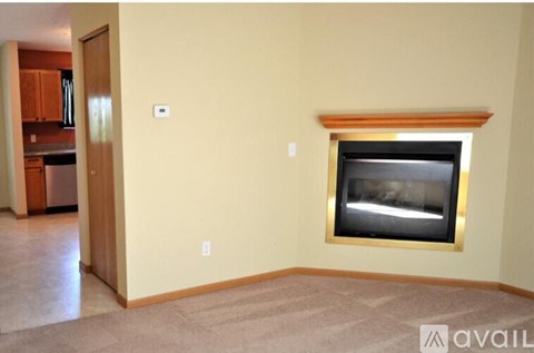 A living room with a fireplace and a doorway leading to a kitchen.