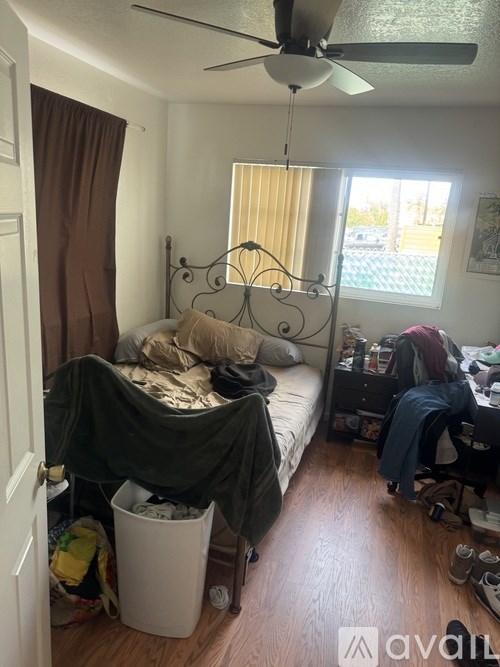 A bedroom with a bed covered in a blanket and a fan above it.