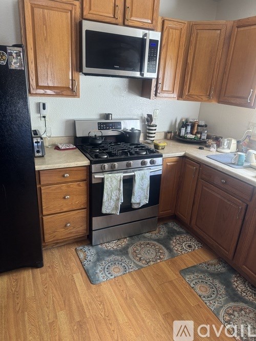 A kitchen with wooden cabinets and a black refrigerator.