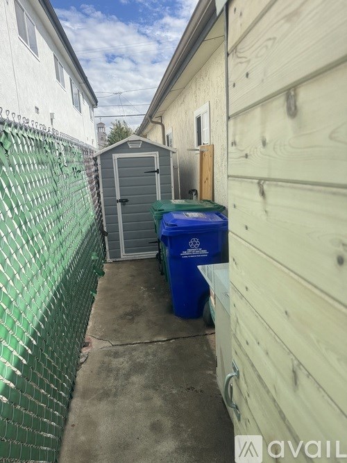 A green fence is on the left of a wooden building.