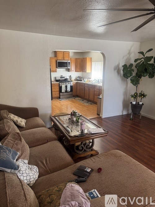A living room with a couch and a coffee table in the foreground and a kitchen in the background.