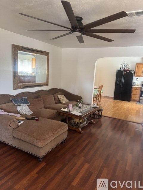 A living room with a brown couch and a ceiling fan.