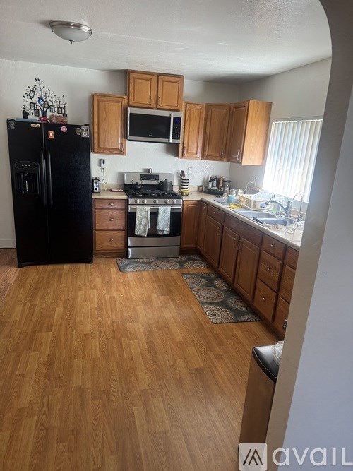 A kitchen with wooden floors and a black refrigerator.