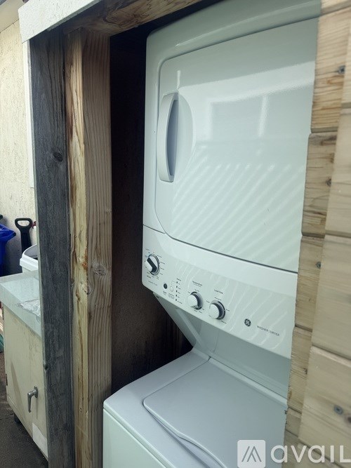 A white washing machine is installed in a wooden wall.