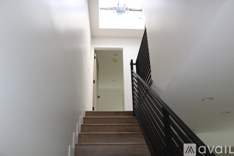 A staircase with a black railing leads to a white door.