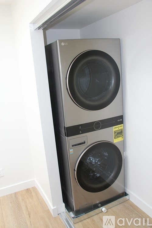A modern front-loading washing machine with a black door is installed in a wall-mounted cabinet.