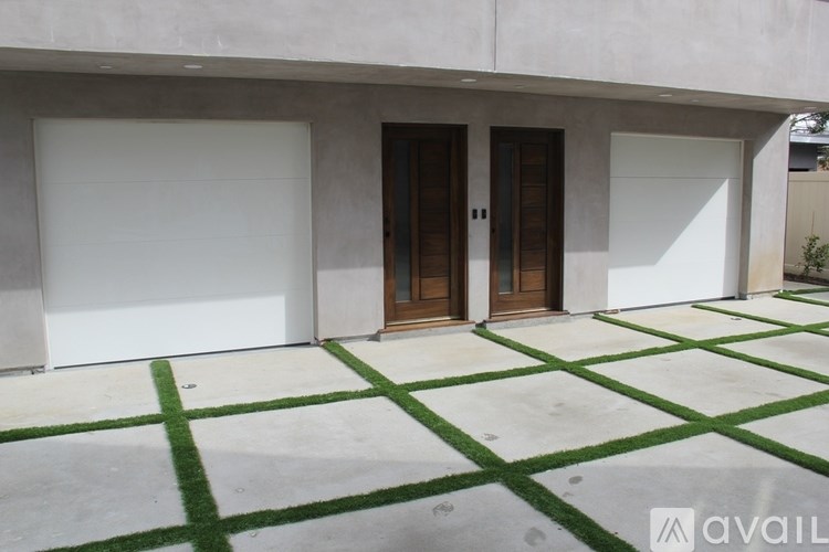 A modern house with a white exterior and a green lawn in front.