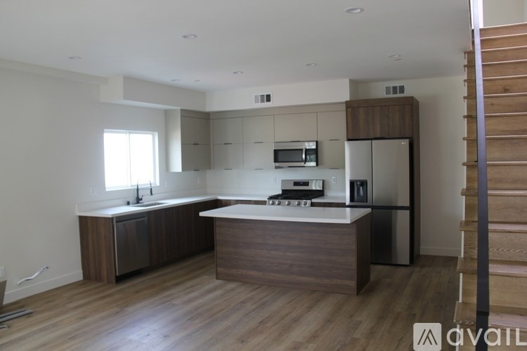 A modern kitchen with wooden floors and stainless steel appliances.