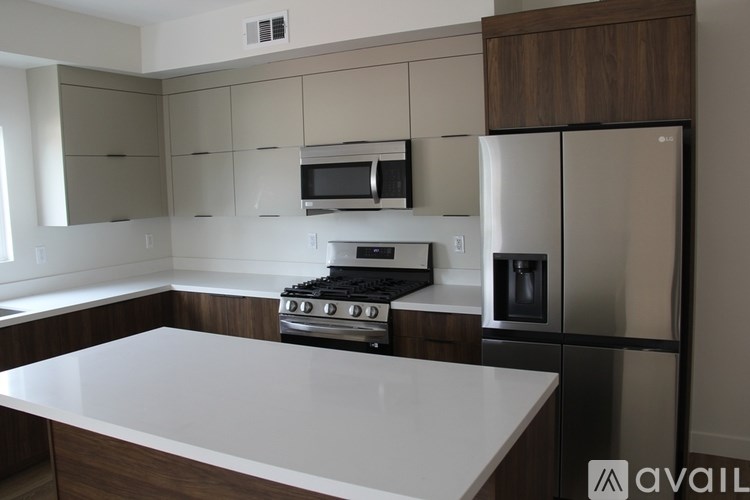 A kitchen with a white countertop and a stainless steel refrigerator.