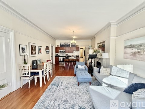 A living room with a white couch and a blue rug.