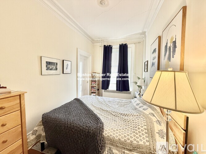 A bedroom with a bed, dresser, and lamp.