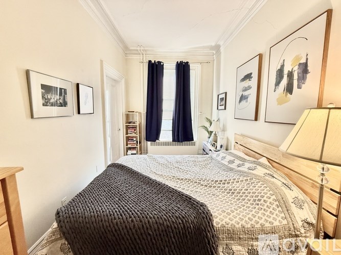 A bedroom with a bed, nightstand, and pictures on the wall.