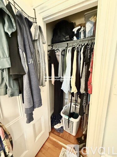 A white closet with clothes hanging and baskets on the floor.