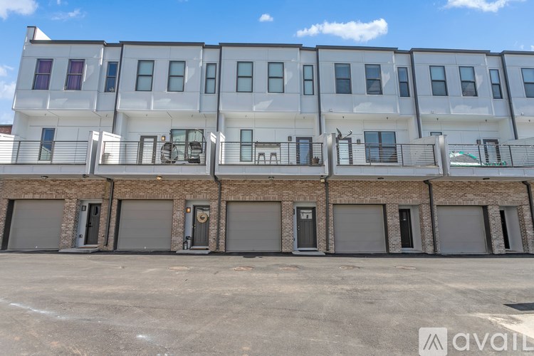 A row of modern townhouses with balconies and garage doors.