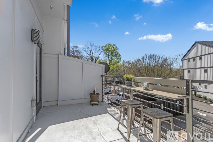 A balcony with a table and chairs overlooks a parking lot.