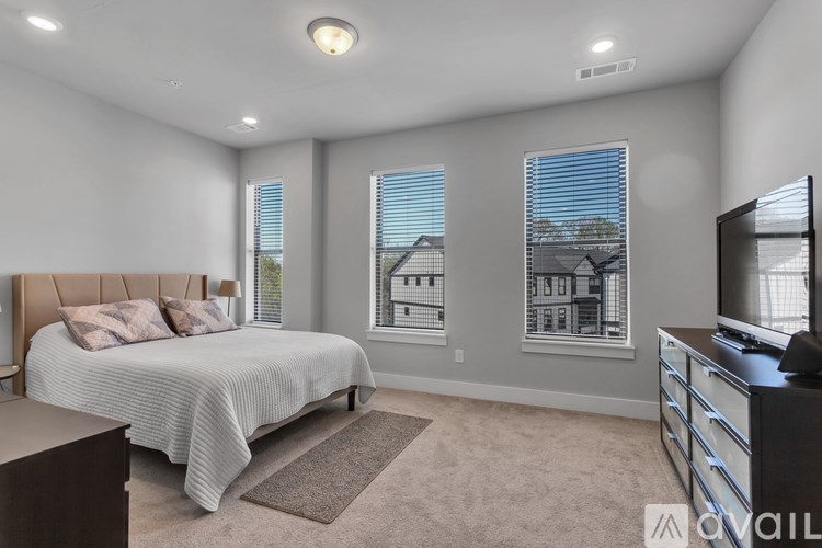 A bedroom with a large bed, a television, and a window with blinds.