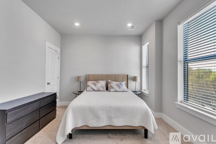 A bedroom with a bed, nightstands, and a window with blinds.