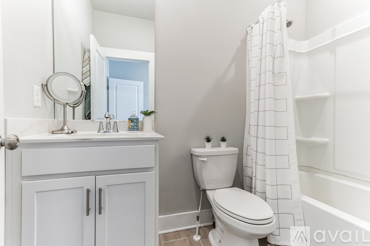 A white bathroom with a toilet, sink, and mirror.