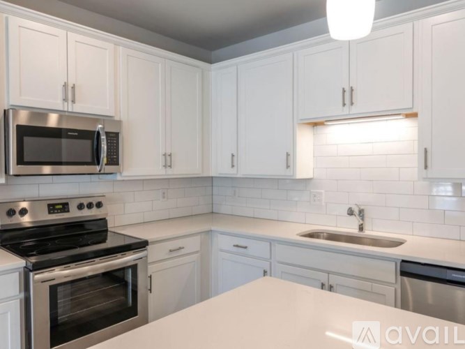 A kitchen with white cabinets and a stainless steel microwave.