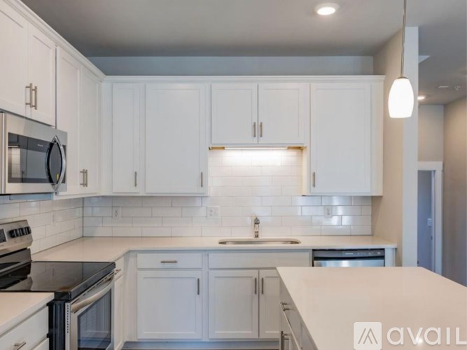 A modern kitchen with white cabinets and stainless steel appliances.
