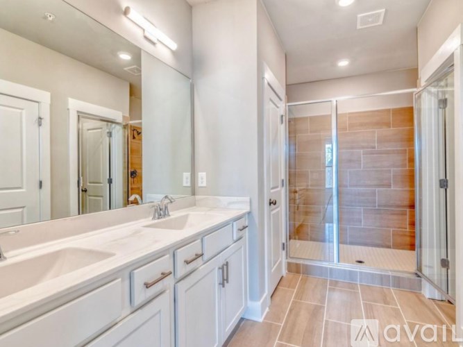 A bathroom with a walk-in shower and double sinks.