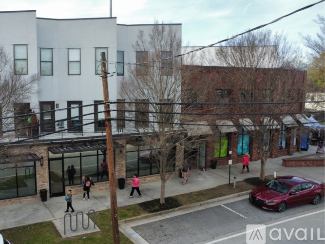 A red car is parked in a parking lot in front of a building.