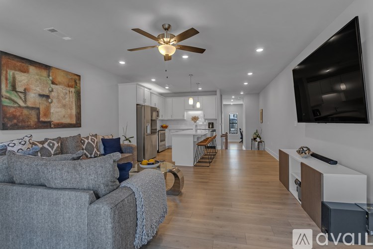 A spacious living room with a grey sofa and a television on the wall.