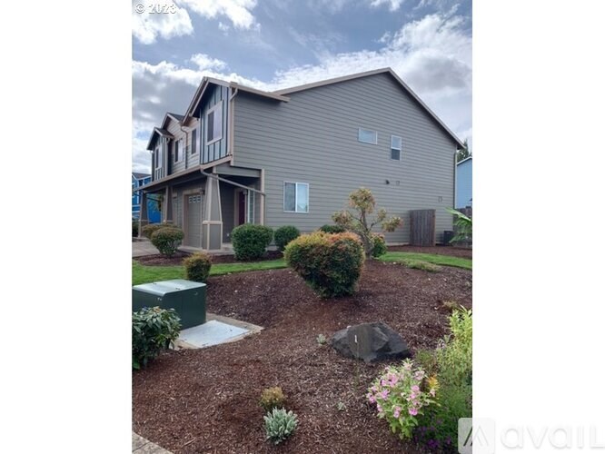 A grey house with a small garden in front.