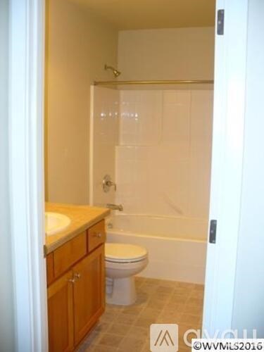 A white toilet sits in a bathroom next to a sink.