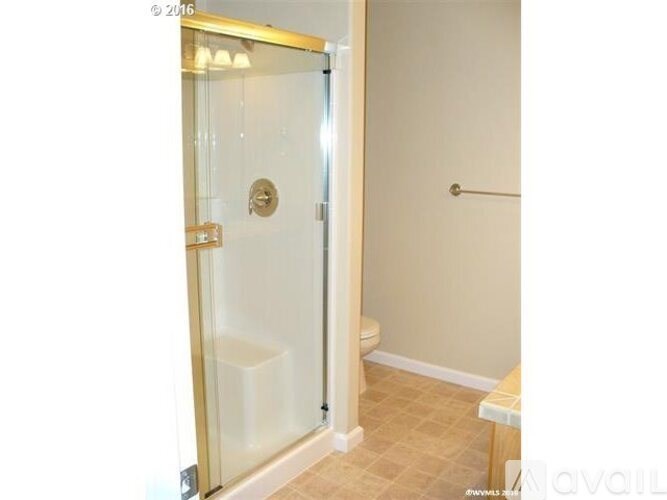 A bathroom with a glass door shower and a white toilet.