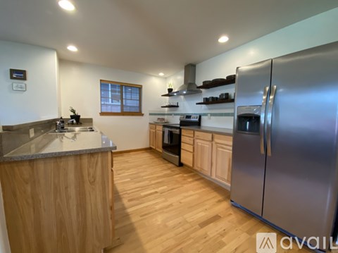 A kitchen with wooden cabinets and a stainless steel refrigerator.