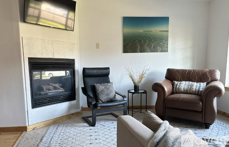 A living room with a fireplace and two chairs.