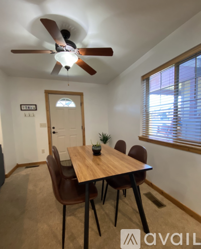 A dining room with a wooden table and brown chairs.