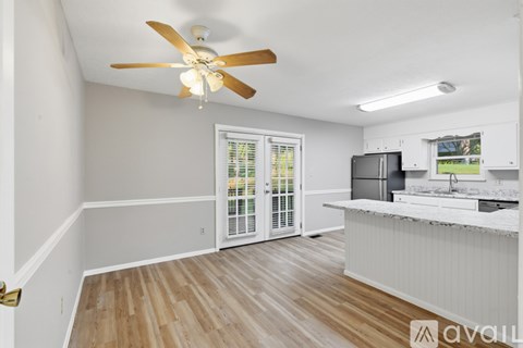 A kitchen with a fan on the ceiling and a window with blinds.