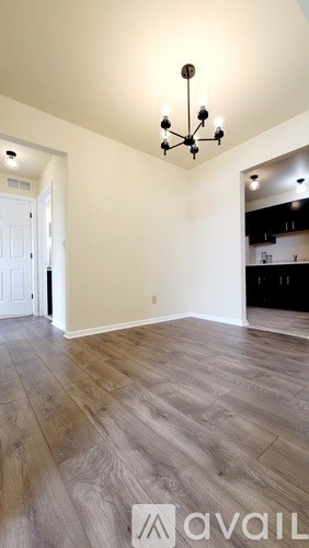 A room with a chandelier and a wooden floor.