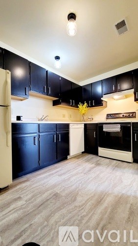 A kitchen with black cabinets and a white refrigerator.