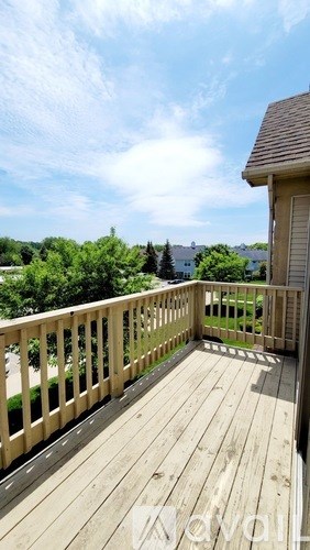 A wooden deck with a railing and a house in the background.