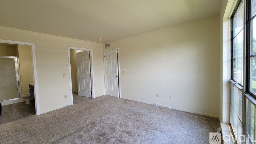 A spacious room with carpeted floor and large windows.