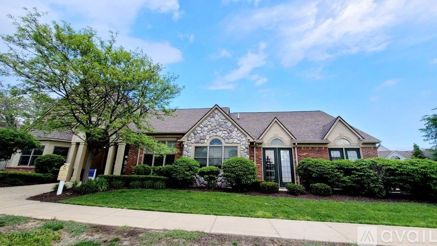 A house with a green lawn and a tree in front of it.