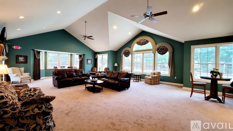 A spacious living room with a dark green wall and a large window.