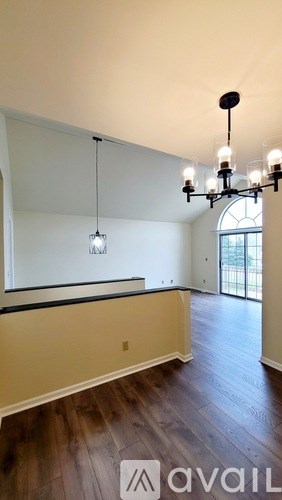A chandelier hangs from the ceiling in a room with hardwood floors.