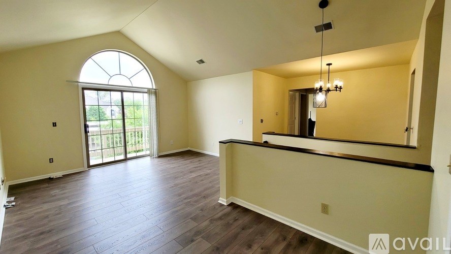 A spacious living room with a large window and hardwood flooring.