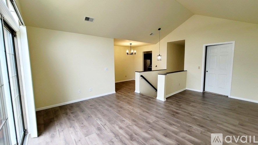 A spacious room with wooden flooring and a white door.