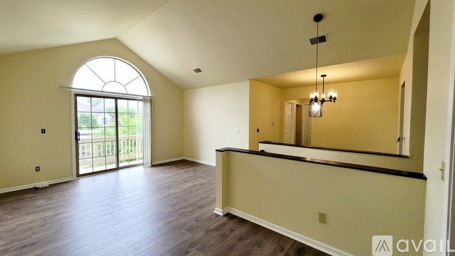 A spacious room with a large arched window and a mirror on the wall.